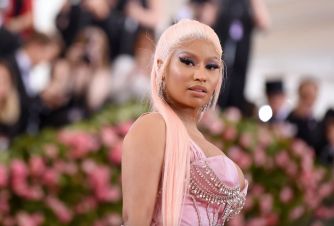 Nicki Minaj at a red carpet event, wearing a pink outfit with long, light pink hair.