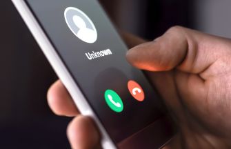 A close-up of a hand holding a smartphone displaying an incoming call from an unknown number.