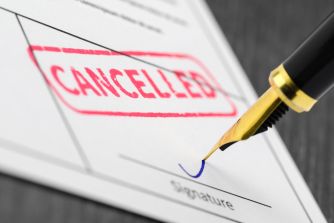 A close-up of a document with the word "CANCELLED" stamped in red, accompanied by a gold pen poised to sign.