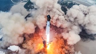 A SpaceX launch rocket taking off amidst a cloud of smoke and flames.