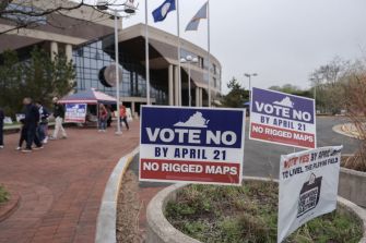Protesters outside a Virginia government building with signs reading “Vote No by April 21” and “No Rigged Maps” opposing redistricting.