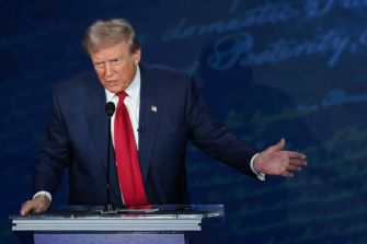 Former President Donald Trump speaking at a podium during a debate.