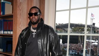 Sean "Diddy" Combs standing indoors with a view of a concert outside.