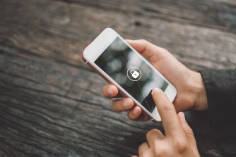 Image of a person holding a locked smartphone with a padlock icon on the screen.