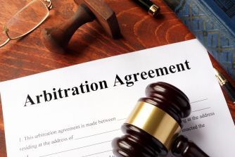 A gavel and an arbitration agreement document placed on a wooden surface.