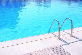 Swimming pool with steps leading into clear blue water.