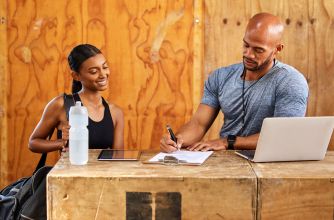 A gym staff member assists a new member with paperwork at a fitness facility.