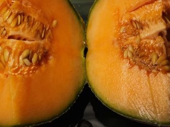 Close-up image of a halved cantaloupe showing its orange flesh and seeds.