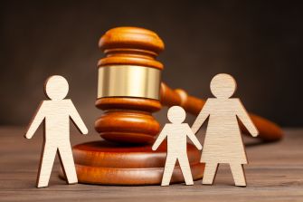 Wooden family figures with a gavel in the background, symbolizing family law and custody cases.