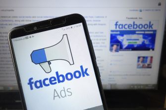 Image of a smartphone displaying the Facebook Ads logo next to a computer screen showing the Facebook homepage.