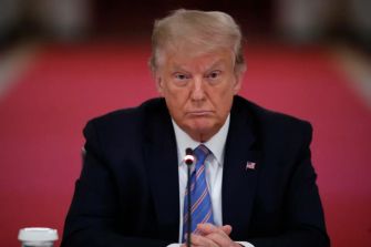 Former President Donald Trump sitting at a table with a serious expression during a meeting.
