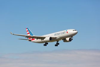 American Airlines passenger jet flying in a clear blue sky.