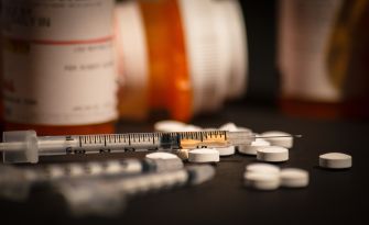A close-up view of prescription pills and syringes, highlighting the opioid crisis and its impact on public health.