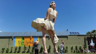A large statue of Marilyn Monroe in a white dress, inspired by a famous film scene, in Palm Springs, California, with tourists posing nearby.