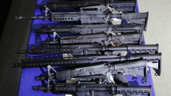 A display of various black firearms arranged horizontally on a table.