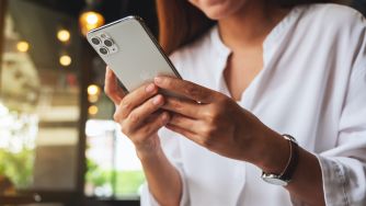 A person holding a smartphone, with a focus on their hands and the device.