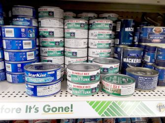 Canned tuna products from various brands displayed on store shelves.