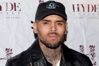 Image of Chris Brown at an event, wearing a black hat and jacket.