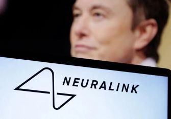 Close-up of the Neuralink logo with a blurred figure in the background.