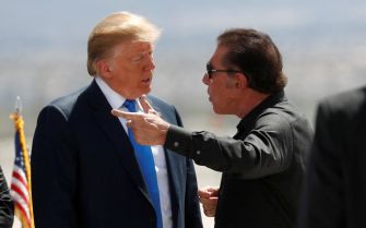 Two men engaged in a conversation, one gesturing while talking to the other.