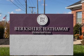 Sign for Berkshire Hathaway HomeServices with a purple and white design, featuring the company's logo.