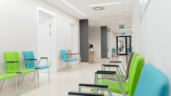 A waiting area in an urgent care center with empty colorful chairs.