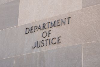Sign on the exterior wall of a building that reads "Department of Justice."