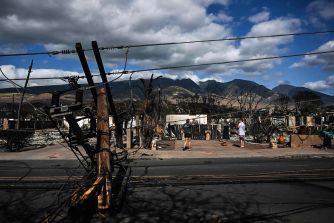 Devastation from the Maui wildfire, showing destruction of buildings and downed power lines in Lahaina.