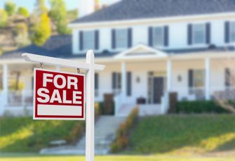 A "For Sale" sign in front of a house with a blurred background.