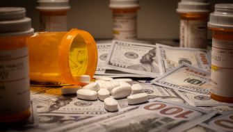 Image of scattered prescription pill bottles and white tablets lying on a surface covered with U.S. currency.