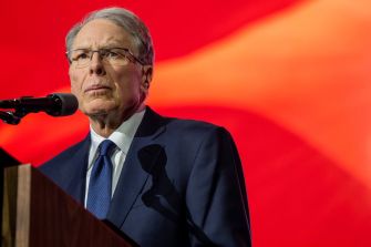 Wayne LaPierre, CEO of the NRA, speaking at a podium with a red background.
