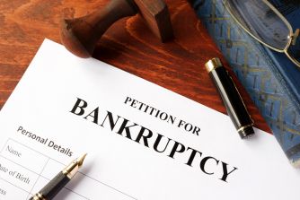 A close-up of a bankruptcy petition form with a gavel and a pen nearby.