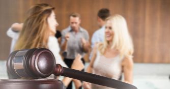 A gavel in the foreground with a blurred background of people socializing, symbolizing changes in the legal system.