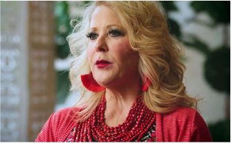 A woman speaking about her experience as an independent retailer with LuLaRoe, dressed in red and wearing statement earrings.
