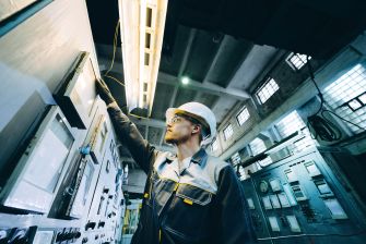 A worker inspecting electrical control panels in an industrial setting.
