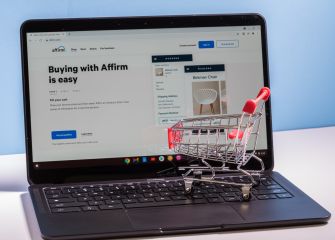 A laptop displaying the Affirm website with a small shopping cart model on the keyboard.