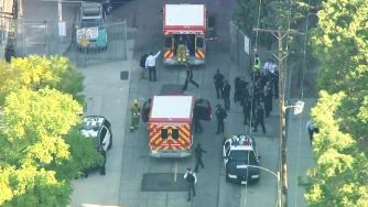 Emergency responders at the scene of a school shooting incident, with police and ambulances present.