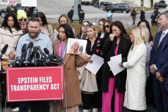 Crowd of reporters and supporters at an outdoor press conference, with a red “Epstein Files Transparency Act” sign and a woman holding a portrait of a smiling blonde.