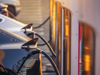 Close-up of electric vehicle charging cables plugged into cars at a charging station.
