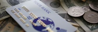 A bank card on top of cash and coins, symbolizing financial fraud.