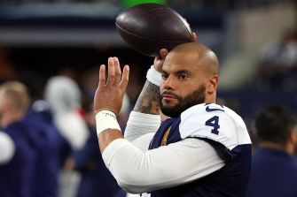 NFL quarterback Dak Prescott throws a football during warm-ups on the field.