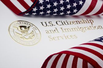 Close-up of a U.S. Citizenship and Immigration Services document with the Department of Homeland Security seal, surrounded by red, white, and blue flag ribbons.