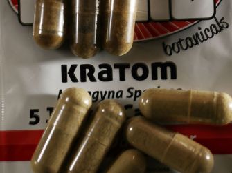 Capsules of kratom on a package labeled with the product name and description.