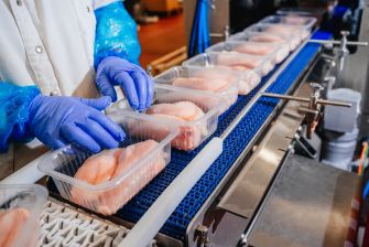 A worker organizing chicken fillets in a meatpacking facility.