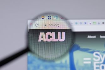 Logo of the American Civil Liberties Union (ACLU) website displayed under a magnifying glass.