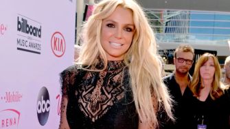 Blonde woman on the red carpet wearing a black lace dress at a Billboard Music Awards event.