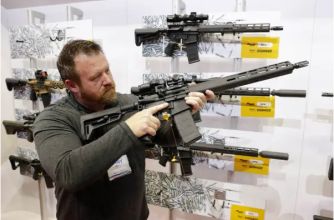 A person examining a modern firearm in a display featuring various rifles.