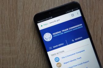 An image of a smartphone displaying the Federal Trade Commission (FTC) website, emphasizing consumer protection resources.