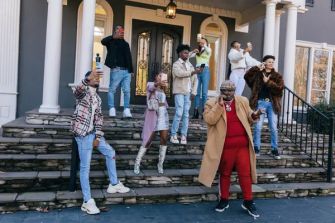 A group of Black TikTok users posing on the steps of a building, some holding smartphones, in a visual representation of their collective action and protest against appropriation of Black culture on the platform.