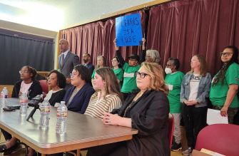 A group of supporters, including a teacher and students, at a press conference holding a sign that reads "LEARNS IS A RUSE."